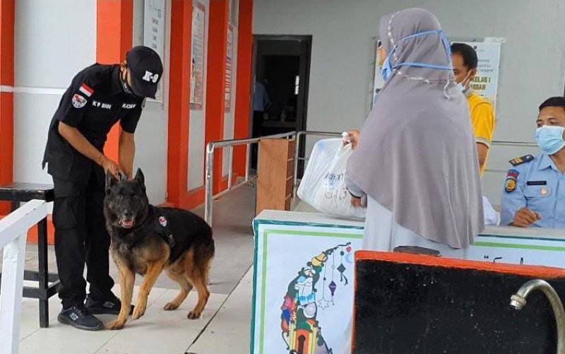 Petugas memegang anjing pelacak K-9 milik BNN Provinsi Sulsel yang disiagakan di depan pintu masuk untuk memeriksa barang titipan bagi narapidana yang akan dibawa masuk ke Rumah Tahanan Negara (Rutan) Kelas 1 Makassar, Sulawesi Selatan, Jumat (14-5-2021). (foto : ANTARA/HO-Rutan Makassar)