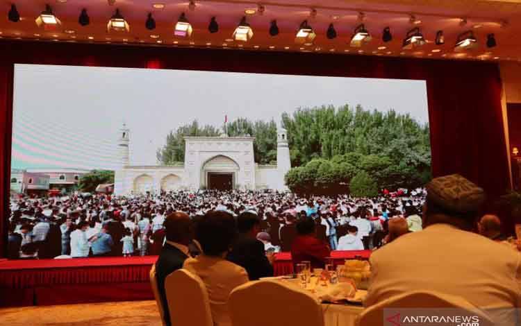Presiden Asosiasi Islam Xinjiang dan Rektor Institut Agama Islam Xinjiang Abdur Raqib Tursuniyaz (membelakangi lensa) dan tamu undangan dari kalangan diplomat asing menyaksikan siaran langsung perayaan Idul Fitri yang dihadiri ribuan umat Islam etnis minoritas Uighur di depan Masjid Idkah, Kota Kashgar, Kamis (13/5/2021)