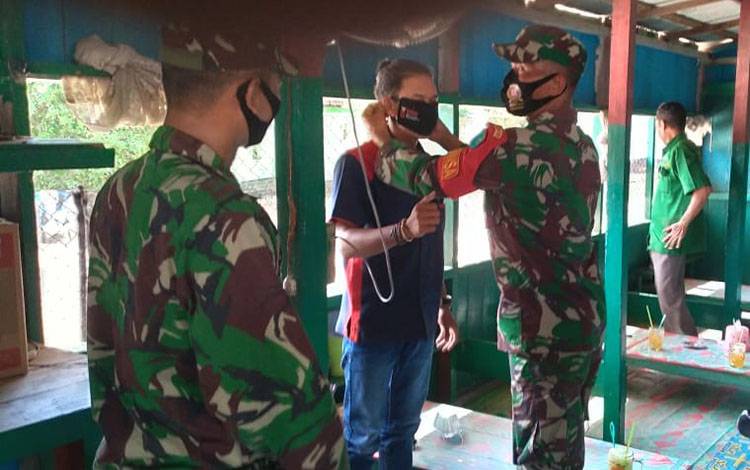 Personel TNI di perbatasan Lamandau (Kalteng)-Kalbar saat melakukan sosialisasi pencegahan Covid-19 dan membagikan masker gratis. 