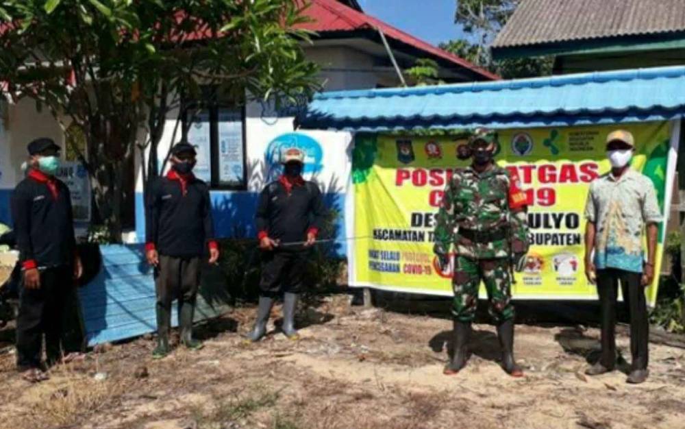 Babinsa Koramil Kapuas Kuala bersama Tim Satgas PPKM Desa Sidomulyo usai menyemprotkan disinfektan di fasilitas publik desa setempat.