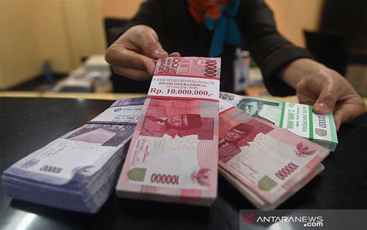 Ilustrasi - Teller menunjukkan uang rupiah yang ditransaksikan. ANTARA FOTO/Sigid Kurniawan/kye.