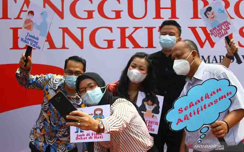Pelaku pariwisata berswafoto usai menjalani vaksinasi COVID-19 tahap pertama di Rumah Sakit Mardiwaloeja, Malang, Jawa Timur, Kamis (20/5/2021). (foto : ANTARA FOTO/Ari Bowo Sucipto)