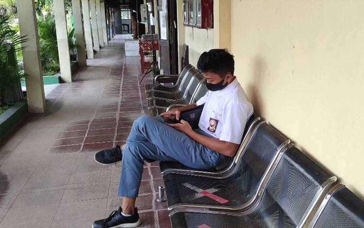 Pelajar di SMAN 4 Palangka Raya saat duduk mengisi waktu luang di selasar sekolah.