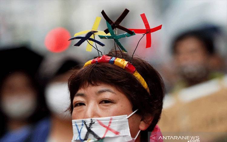Seorang anggota kelompok anti-Olimpiade meneriakkan slogan sambil memakai masker pelindung saat protes di tengah penyebaran penyakit virus korona (COVID-19) di Tokyo, Jepang, Sabtu (19/6/2021). REUTERS/Issei Kato/rwa/cfo
