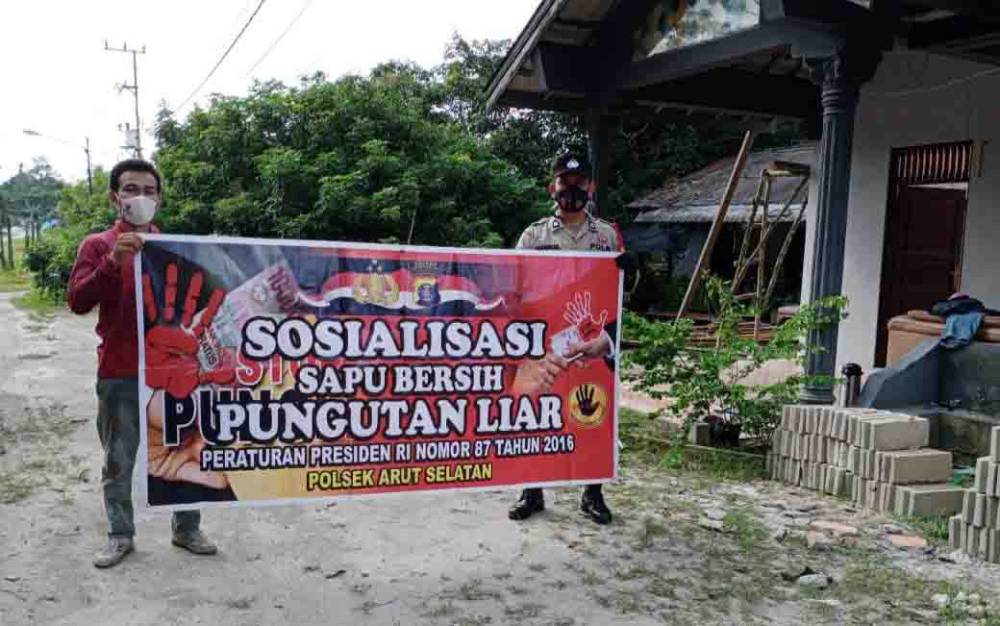 Personel Polsek Arsel membentangkan spanduk sosialisasi Sapu Persih Pungli.