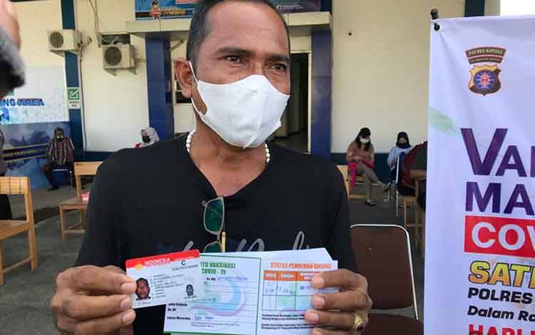 Salah satu warga saat menunjukkan kartu telah menerima vaksinasi di Satlantas Polres Kapuas, Rabu, 23 Juni 2021.