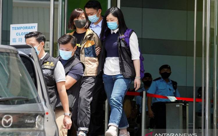 Polisi dari departemen keamanan nasional mengawal Wakil Pemimpin Redaksi Apple Daily Chan Pui-man dari kantor Apple Daily dan Next Media di Hong Kong, China, Kamis (17/6/2021)