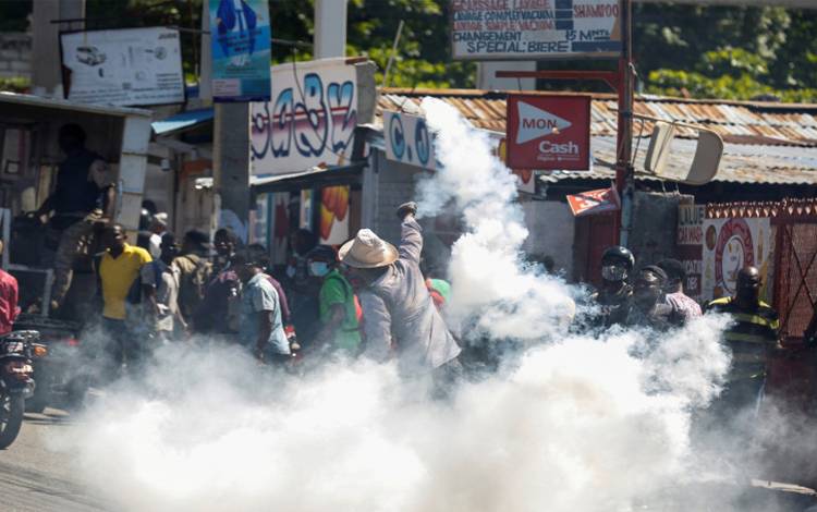 Seorang pria melempar tabung gas air mata balik ke arah polisi saat protes terhadap Presiden Haiti Jovenel Moise di Port-au-Prince, Haiti, Rabu (10/2/2021)