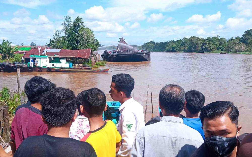 Masyarakat yang meyaksikan proses pemadaman tongkang milik PT Korindo yang terjadi di pinggiran Sungai Arut, Pangkalan Bun, Kobar, Senin, 5 Juli 2021