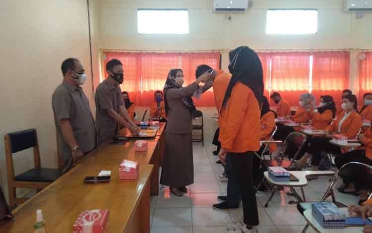 Wakil STIE-DD Buntok, Harlina Kurniaty memasang tanda peserta mahasiswa KKN.