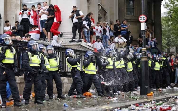 Polisi menjadi target pelemparan kaleng bir ketika suporter Inggris berkumpul di Lapangan Trafalgar dalam nonton bareng final UEFA EURO 2020 antara Inggris dan Italia di pusat kota London pada 11 Juli 2021. (Photo by Tolga Akmen / AFP)