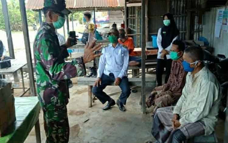 Personel Koramil Kapuas Timur saat memberikan edukasi terkait prokes di Desa Anjir Serapat Tengah.