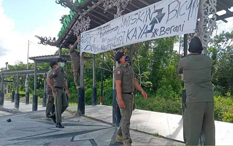 Petugas saat menurunkan spanduk provokatif protes Covid-19 di Palangka Raya, Selasa, 13 Juli 2021.