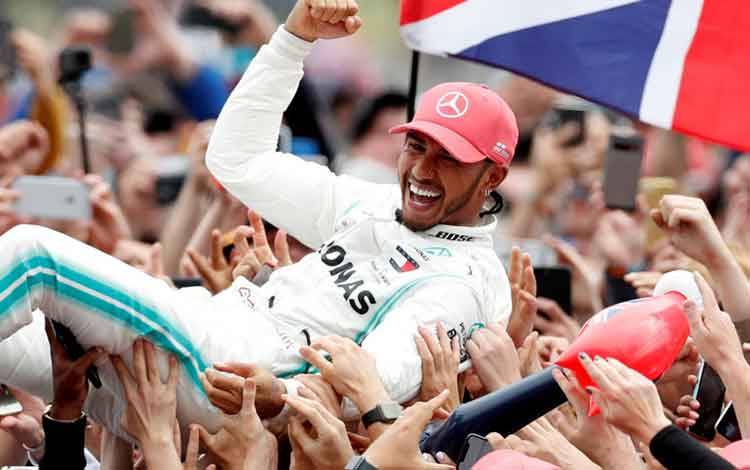 Pebalap tim Mercedes Lewis Hamilton melakukan selebrasi setelah menjuarai Grand Prix Inggris di Sirkuit Silverstone. (14/7/20219) (ANTARA/REUTERS/Matthew Childs)