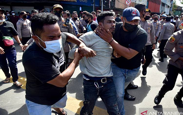 Sejumlah petugas polisi berpakaian preman mengamankan seorang demonstran yang diduga provokator saat membubarkan unjuk rasa di Kota Ambon, Provinsi Maluku, Jumat (16/7/2021)
