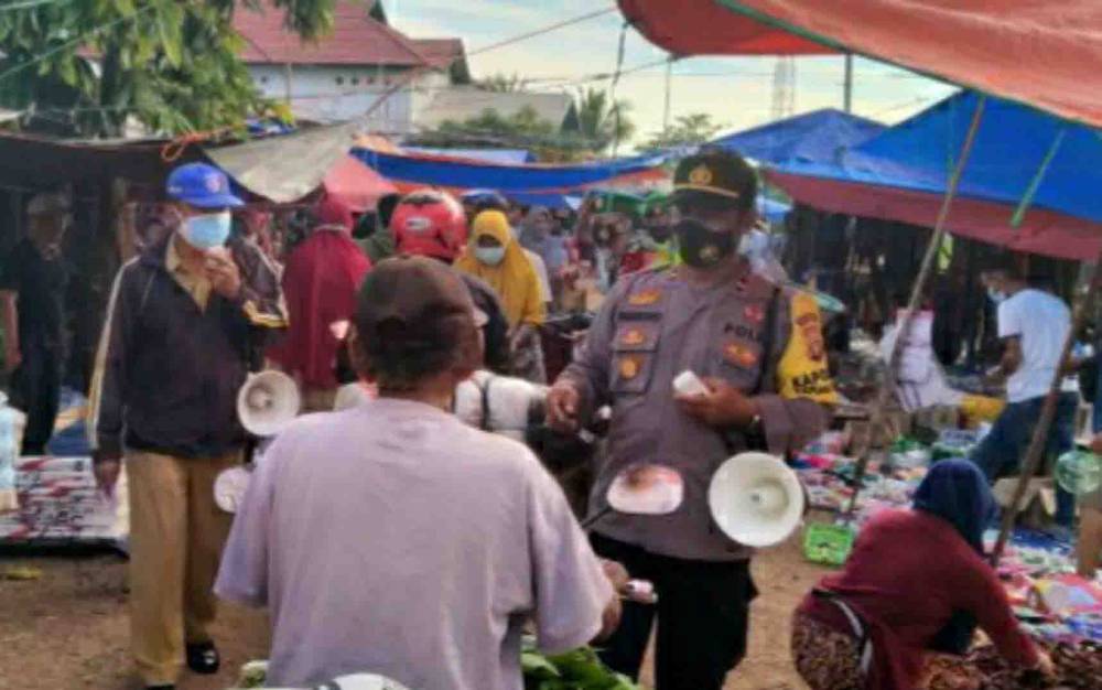 Kapolsek Kapuas Kuala, Ipda Parmono saat memberikan imbauan penerapan prokes di kawasan Pasar Tradisional pada Senin, 19 Juli 2021.