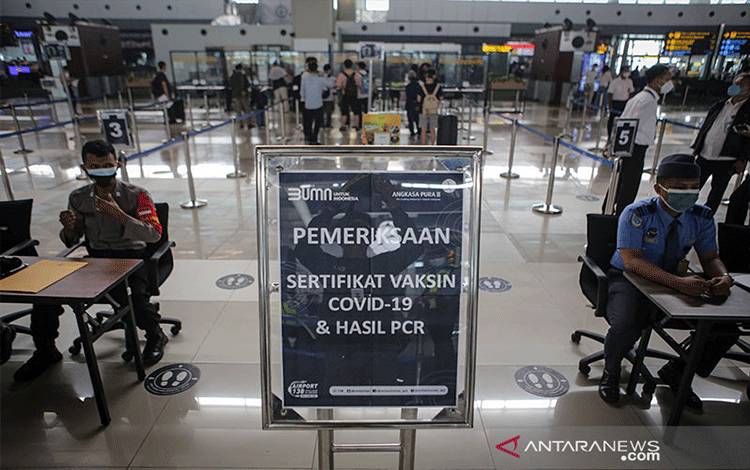 Petugas memeriksa surat vaksinasi dan hasil tes PCR calon penumpang pesawat sebelum melakukan penerbangan di Terminal 3 Bandara Internasional Soekarno Hatta, Tangerang, Banten, Senin (5/7/2021). Pemerintah mulai memberlakukan syarat penerbangan pada masa PPKM Darurat, yaitu kewajiban membawa surat vaksin minimal dosis pertama dan hasil negatif tes PCR yang sampelnya diambil pada H-2 keberangkatan sebagai upaya menekan penyebaran COVID-19. ANTARA FOTO/Fauzan/pras. (ANTARA FOTO/FAUZAN)