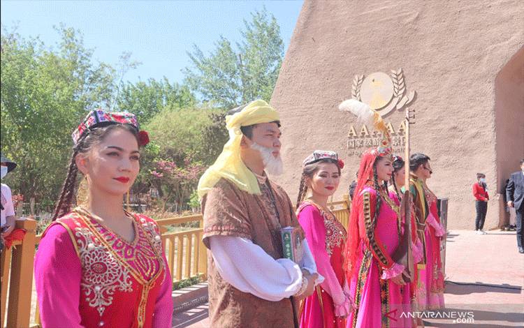 Perempuan etnis minoritas Muslim Uighur menyambut para wsiatawan di gerbang Kota Tua Kashgar, wilayah selatan Daerah Otonomi Xinjiang, China, Senin (19/4/2021). Sektor pariwisata di Kashgar masih belum sepenuhnya pulih sehingga pemerintah daerah setempat bekerja keras dengan menambah daya tarik wisata. ANTARA FOTO/M. Irfan Ilmie