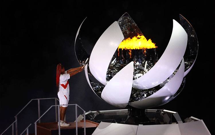 Petenis dunia asal Jepang Naomi Osaka menjadi pembawa obor terakhir untuk menyulut api ke kaldron Olimpiade Tokyo yang menyerupai bunga sakura dalam rangkaian upacara pembukaan di Stadion Nasional, Tokyo, Jepang, Jumat (23/7/2021). (ANTARA/REUTERS/Leah Millis)
