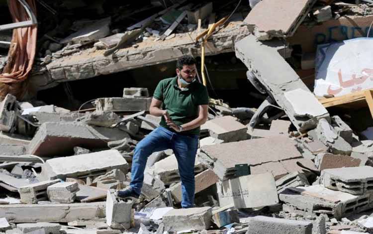 Warga Palestina Shaban Esleem berada di antara reruntuhan toko bukunya yang hancur akibat serangan udara Israel selama pertempuran Israel-Palestina, di Kota Gaza, Senin (24/5/2021)
