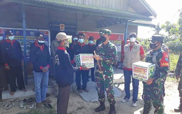 Dandim 1011 Kuala Kapuas, Letkol Inf Ary Bayu Saputro saat menyerahkan bantuan sembako kepada petugas PPKM mikro di Desa Sidomulyo.