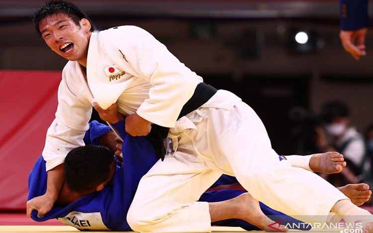 Taekwondoin Jepang Takanori Nagase (atas) saat tampil dalam perebutan medali emas kelas +81kg putra Olimpiade Tokyo 2020 melawan wakil Mongolia Saeid Mollaei di Nippon Budokan, Tokyo, Selasa (27/7/2021)