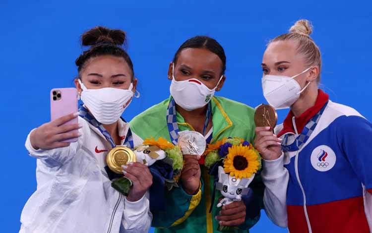 Peraih emas senam semua alat Sunisa Lee dari Amerika Serikat berselfie dengan peraih medali perak Rebeca Andrade dari Brazil dan peraih medali perunggu Angelina Melnikova dari ROC/Rusia dalam senam Olimpiade Tokyo 2020 di Ariake Gymnastics Centre, Tokyo, Jepang, 29 Juli 2021