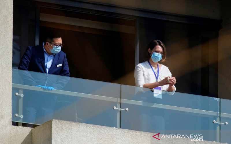 Anggota (kanan) tim Organisasi Kesehatan Dunia (WHO) yang bertugas menyelidiki asal mula virus corona (COVID-19) berada di balkon sebuah hotel di Wuhan, provinsi Hubei, China, 2021. (foto : REUTERS/Aly Song)