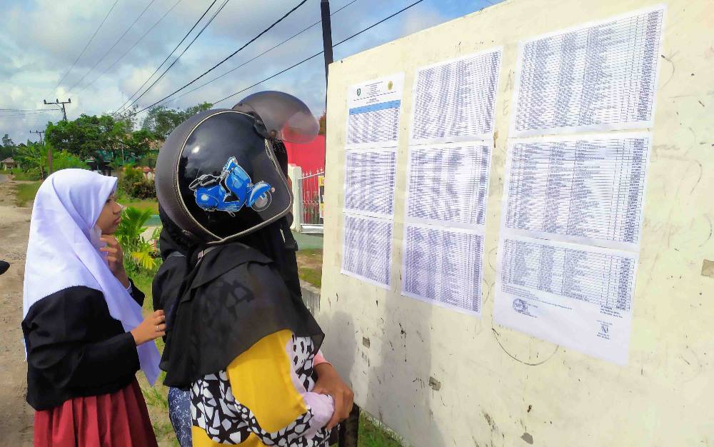 Salah satu orang tua mengantar anaknya melihat pengumuman seleksi peserta didik baru di salah satu SMP di Sampit, beberapa waktu lalu.