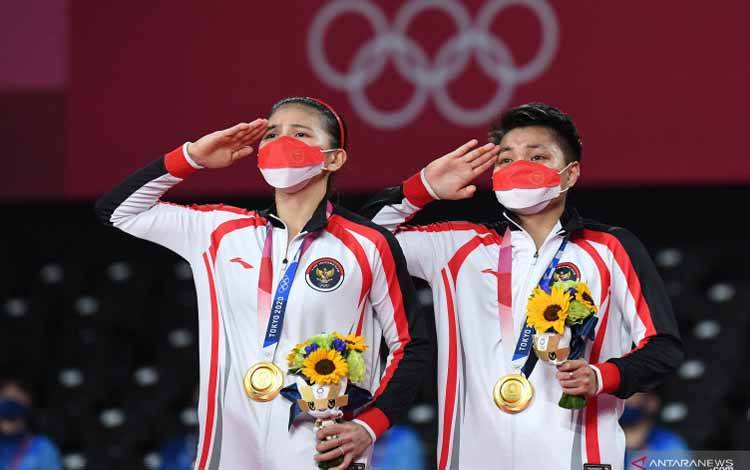 Pebulu tangkis ganda Putri Indonesia peraih medali emas Greysia Polii/Apriyani Rahayu memberi hormat saat pengibaran bendera Merah Putih pada upacara pemberian medali Olimpiade Tokyo 2020 di Musashino Forest Sport Plaza, Tokyo, Jepang, Senin (2/8/2021)
