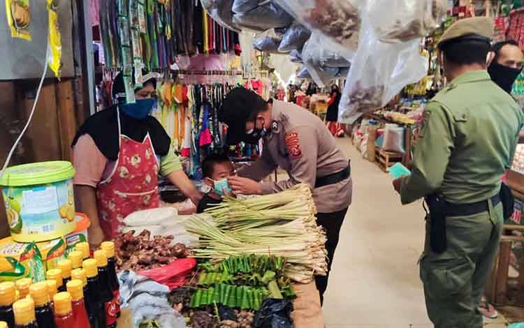 Petugas memberikan memasangkan kepada salah satu anak pedagang di pasar.