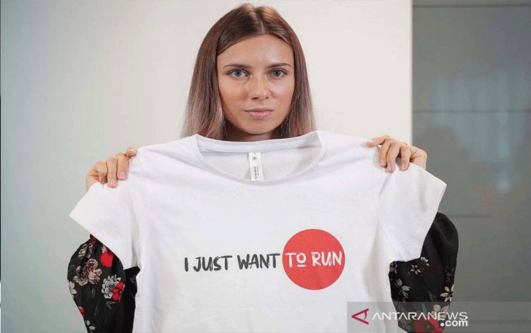 Pelari Belarus Krystsina Tsimanouskaya, yang meninggalkan Olimpiade di Tokyo dan mencari suaka di Polandia, memegang t-shirt pada konferensi pers di Warsawa, Polandia (5/8/2021). ANTARA FOTO/REUTERS/Darek Golik/aww.