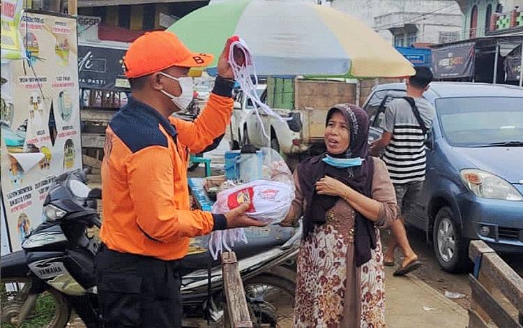 Personel BPBD Damkar Barito Timur membagikan masker di Pasar Ampah, Jumat, 13 Agustus 2021.