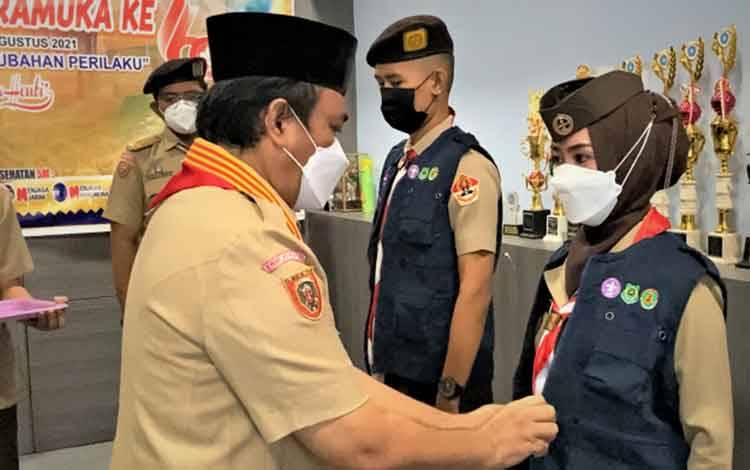 Ketua Kwarcab Gerakan Pramuka Kapuas, Suwarno Muriyat memasang rompi duta perubahan perilaku covid-19 kepada Andalan Cabang, Fahriati dalam peringatan Hari Pramuka ke-60