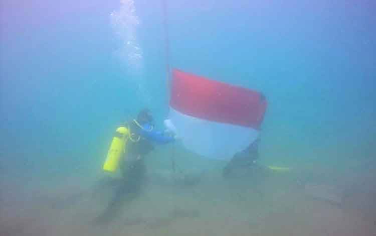 Penyelam mengibarkan bendera merah putih dari dasar laut perairan Pantai Ujong Batee, Kecamatan Muara Dua, Kota Lhokseumawe, Selasa (17/8/2021) ANTARA/HO/Dok Korem 011/Lilawangsa