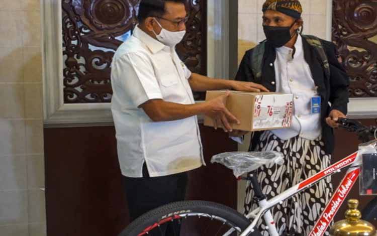 Kepala Staf Kepresidenan Moeldoko memberikan hadiah sepeda dari Presiden Joko Widodo kepada pejalan kaki asal Wonosobo Mahmudin, di Gedung Bina Graha, Jakarta, Rabu (18/8/2021)