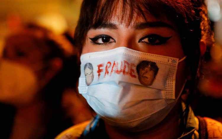 Seorang warga memakai masker bertuliskan "Fraud" saat para pengunjuk rasa beraksi di La Paz, Bolivia, Senin (15/3/2021). Mereka mengecam pemerintahan Presiden Bolivia Luis Arce setelah penahanan mantan Presiden sementara Jeanine Anez