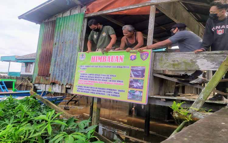 Petugas BKSDA dibantu warga memasang papan imbauan waspada keberadaan buaya di Sungai Mentaya