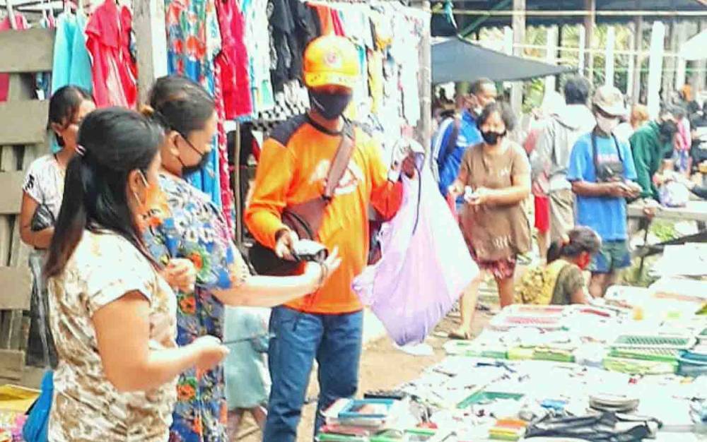 Anggota BPBD Damkar Barito Timur membagikan masker kepada pengunjung Pasar Dayu, Rabu, 25 Agustus 2021.