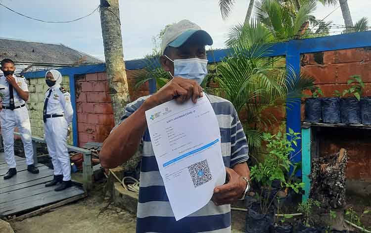 Seorang nelayan Kumai, Zalek (42) menunjukkan hasil keterangan vaksin dosis pertama di Pos TNI AL Kumai.