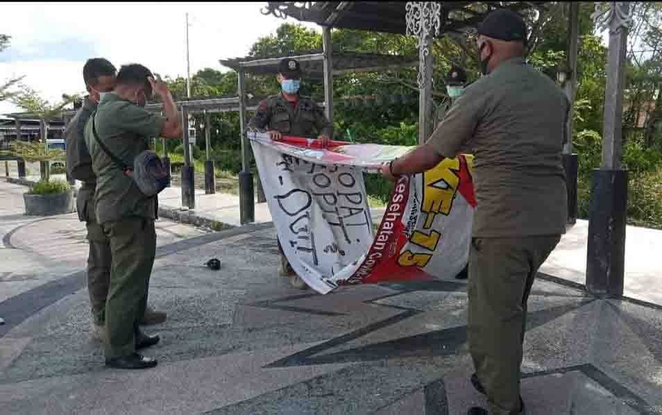 Personel Satpol PP Palangka Raya menertibkan spanduk meresahkan terkait covid-19.