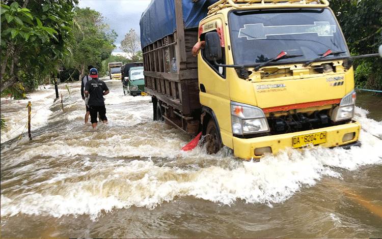 Puluhan kendaraan melintasi Jalan Trans Kalimantan Kasongan - Kereng Pangi tepatnya Km 1 yang terendam banjir dengan dan berarus deras.