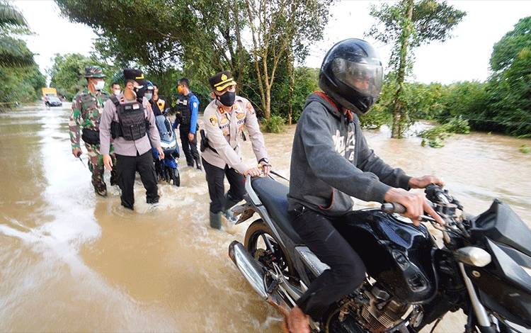 Kapolres Seruyan AKBP Bayu Wicaksono, saat membantu mendorong kendaraan yang melintas di lokasi genangan banjir, Rabu, 15 September 2021.