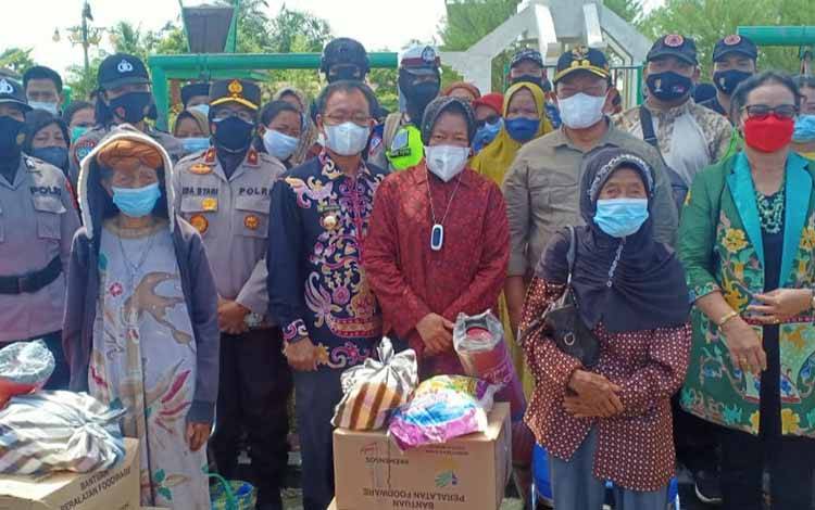 Menteri Sosial RI Tri Rismaharini foto bersama Bupati Katingan Sakariyas dan perwaiikan warga terdampak banjir disela memberikan bansos.
