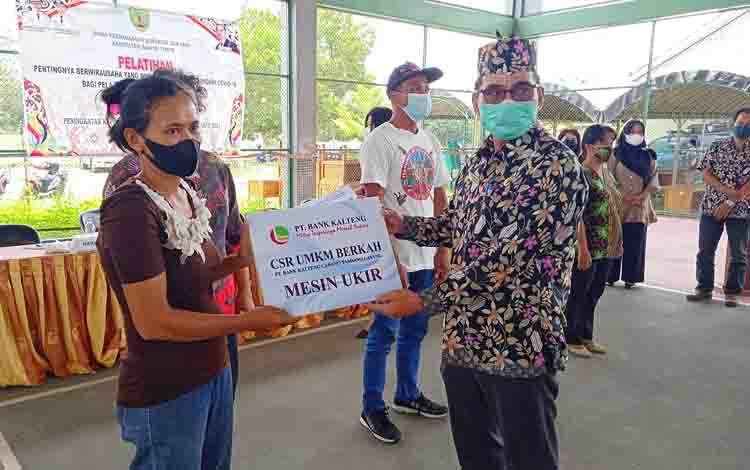 Plt Kepala Dinas Perdagangan, Koperasi dan UKM Kabupaten Barito Timur, Kariato menyerahkan secara simbolis bantuan dari Bank Kalteng kepada pelaku usaha.