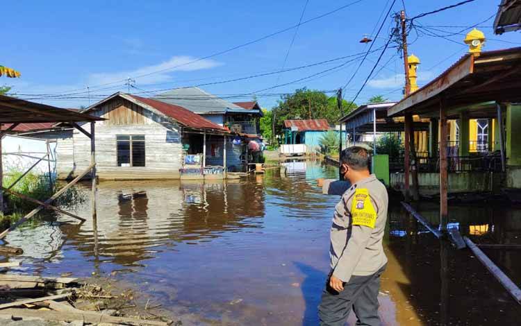 Bhabinkamtibmas Polsek Pahandut Aipda Agus Triyanto saat mengecek kondisi air di permukiman warga