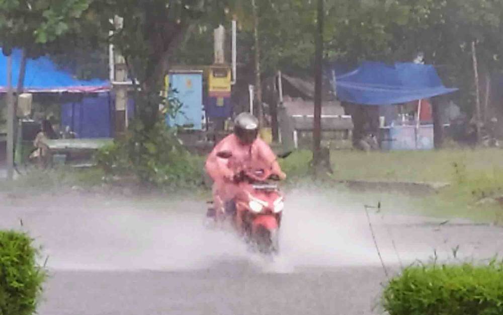 FOTO DOKUMEN- Salah seorang pengguna jalan melintasi terpaan hujan dan genangan air di Kota Sampit, Kotawaringin Timur.