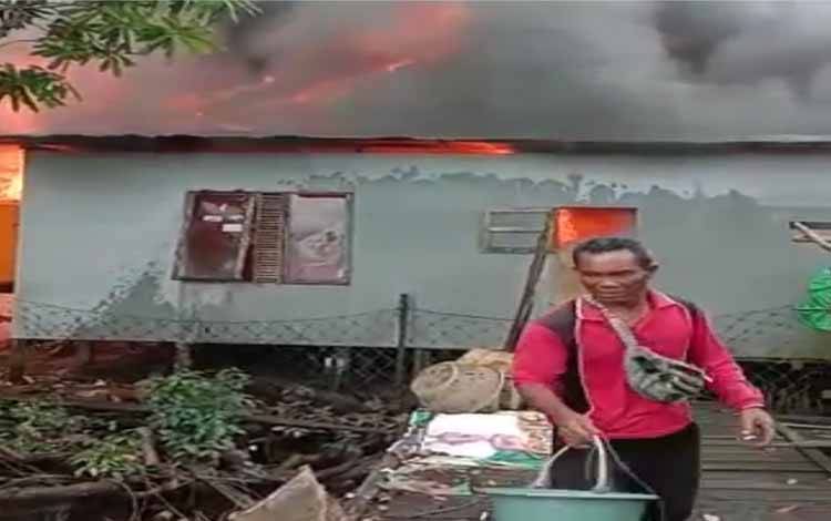 Warga saat berupaya memadamkan api yang membakar rumah di Desa Pulau Hanaut menggunakan ember