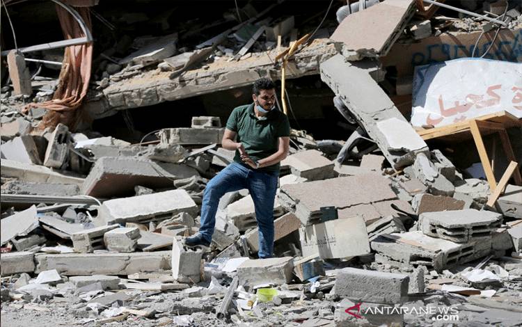 Warga Palestina Shaban Esleem berada di antara reruntuhan toko bukunya yang hancur akibat serangan udara Israel selama pertempuran Israel-Palestina, di Kota Gaza, Senin (24/5/2021). REUTERS/Ibraheem Abu Mustafa/HP/djo