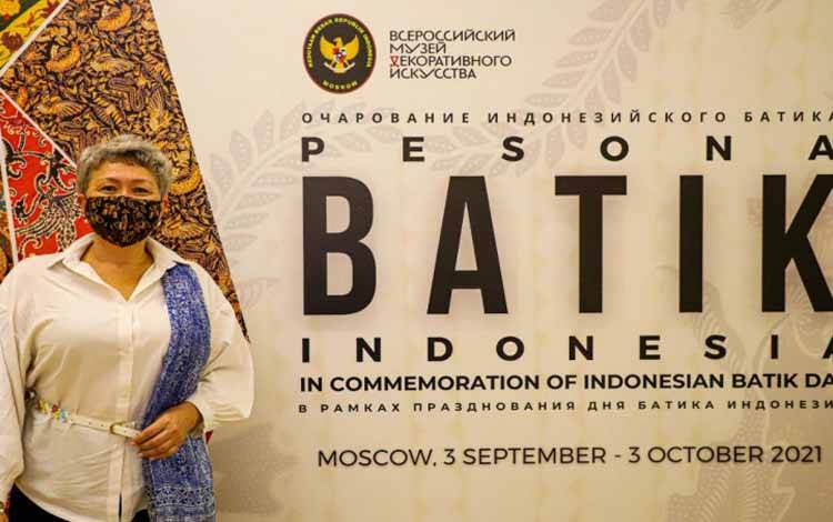 Seorang pengunjung pameran batik Indonesia berpose sambil mengenakan atribut batik
